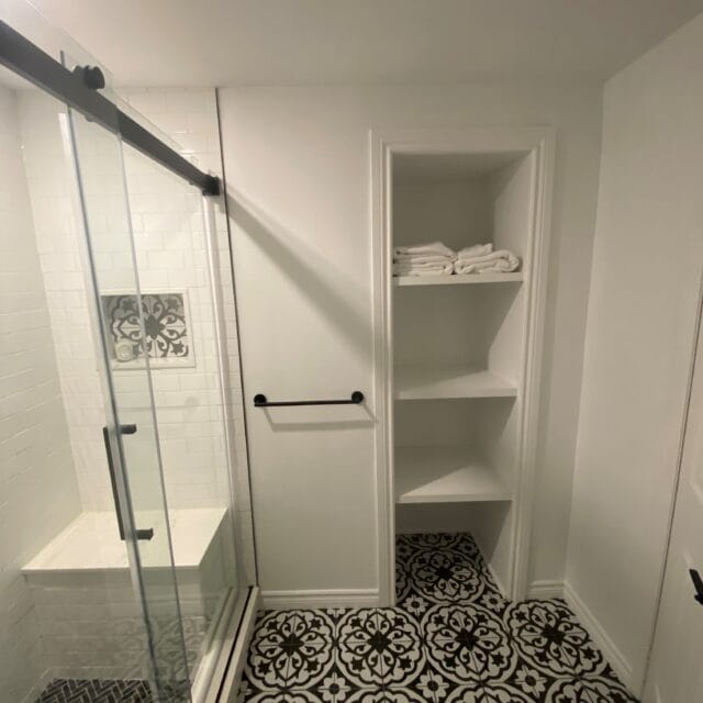 Sliding glass shower with a bench, built-in shelves and patterned floor