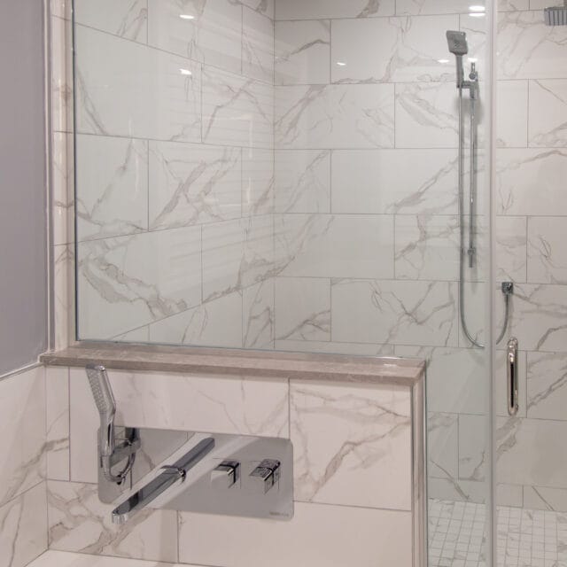 Glass shower with a tiled half wall and wall-mount tub filler