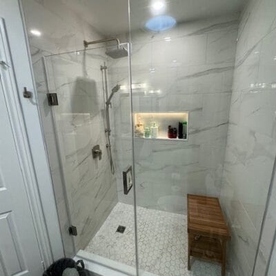 Glass shower with a lit niche, rain head and teak bench