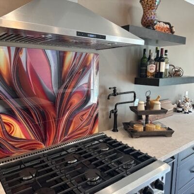 Kitchen gas range under a stainless hood with a glass backsplash
