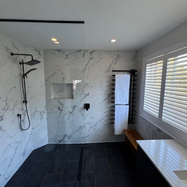 Walk-in shower with a glass panel, linear drain and towel rack