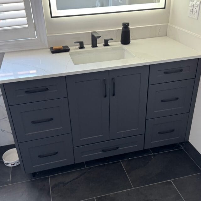 Grey shaker vanity with a quartz top and black faucet