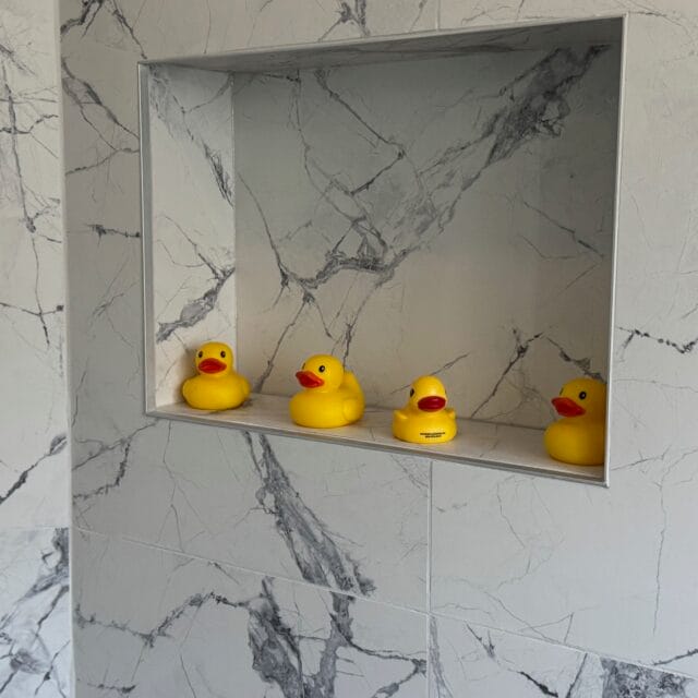 Tiled shower niche holding Hayes Plumbing rubber ducks
