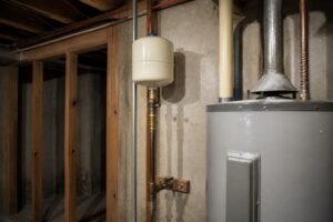 Water heater expansion tank mounted on the cold supply line next to a residential gas water heater.